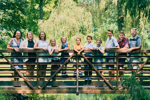 Glückliche elfköpfige Familie steht auf Brücke im Park — Stockfoto