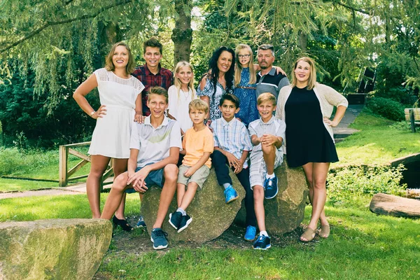 Porträt einer glücklichen elfköpfigen Familie unter Baum — Stockfoto