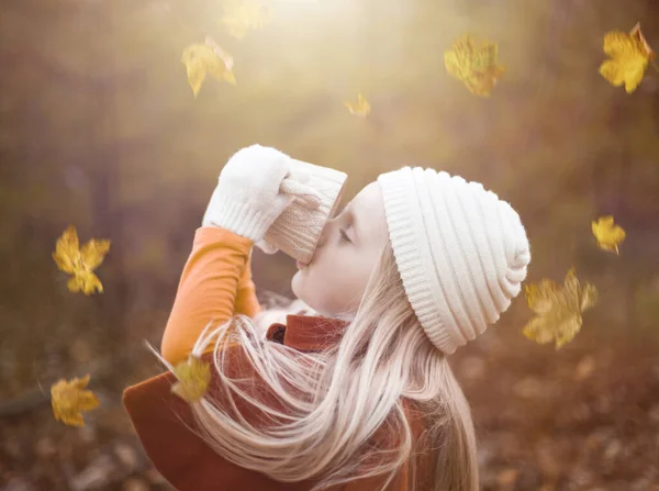 Portrait of little girl drinking tea among leaves — Stock Photo, Image