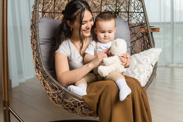 Mutlu anne ve bebek hasır sandalyede sallanıyor.