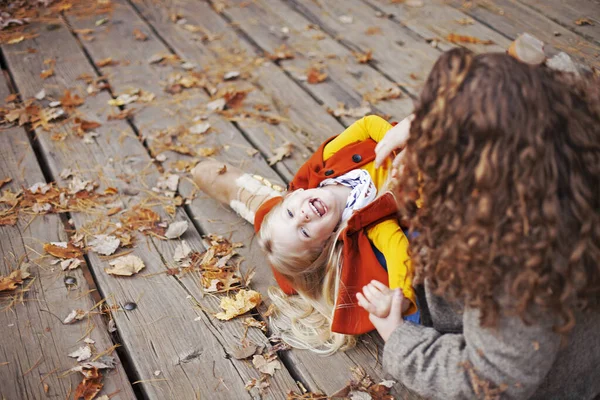 在秋天 兴奋的女孩与母亲共度时光 女人坐在木地板上 女儿躺在她的圈圈上笑着 — 图库照片
