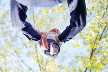 Baba, gülen oğlunu elinde tutuyor. Erkek ellerinin küçük çocuğu fırlattığı görünürde yok. Çocukluk ve babalık kavramı