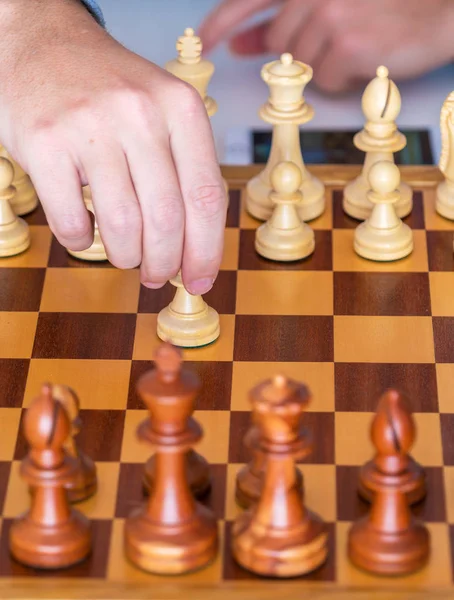 Hand with pawn makes first move on chess Board
