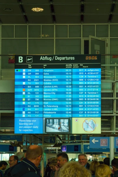 Passengers stand in front of the departure schedule — Stock Photo, Image