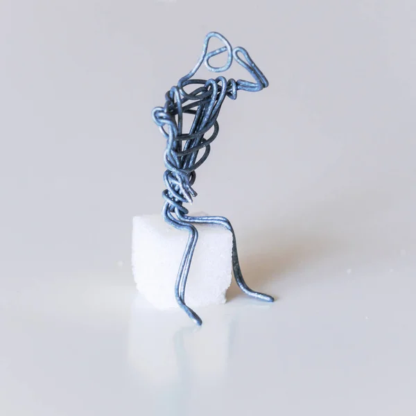 A man of wire sits in the pose of a thinker, raising his hand to his forehead, symbolizing reflection, thoughtfulness, mind, wisdom, knowledge and the search for meaning