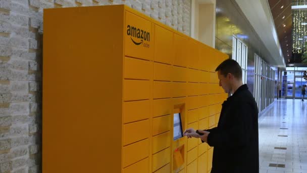 Человек забирает пакет в торговом центре на Amazon Locker Station — стоковое видео
