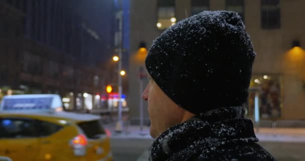 Mannen i snöstorm ser på byggnader på 5th Avenue på Manhattan — Stockvideo