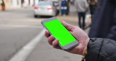 Kadın tutar yeşil ekran Smartphone bir şehirde