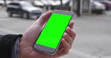 Adam yeşil ekran Smartphone bir şehirde tutar.