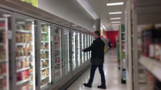 Hombre en las tiendas de comestibles en la sección de alimentos congelados — Vídeo de stock