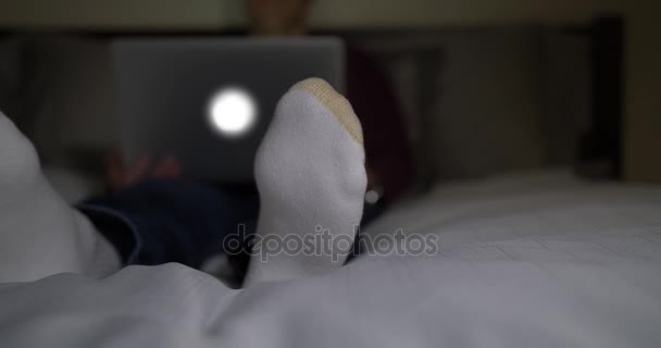 Человек смотрит фильм на ноутбуке в темной спальне — стоковое видео