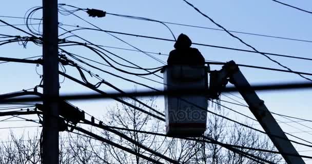 Silhouet elektrische werknemer onderzoekt een telefoon paal — Stockvideo