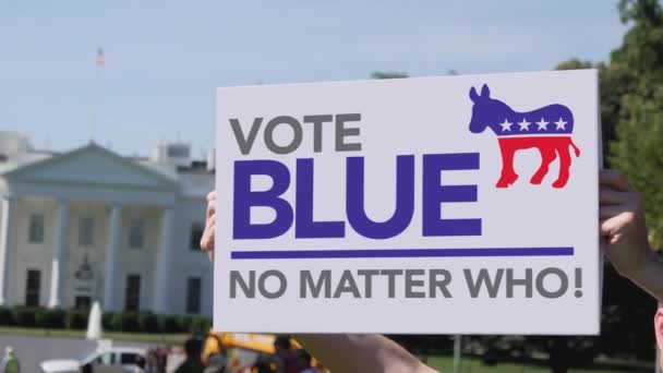 A man holds a Vote Blue No Matter Who election protest sign in front of the White House on a sunny summer day. Social commentary concept.  
