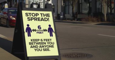 Büyük bir şehrin kaldırımındaki bir tabela yayaları birbirlerinden 2 metre uzak durmaları konusunda uyarıyor. 2020 Coronavirus COVID-19 salgını sırasında halk arasında yaygın bir uygulama haline geldi..  