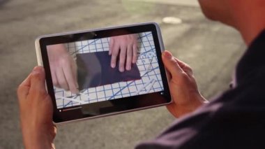Bir adam tabletinde ev yapımı yüz maskesi yapma videosu izliyor. 2020 'deki COVID-19 salgını sırasında hastalığın yayılmasını yavaşlatmak için maskeler yaygın bir görüntüydü..  