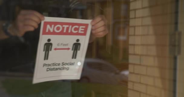 Bir Adam Dükkanının Kapısına Sosyal Mesafe Tabelası Asıyor Sosyal Fiziksel — Stok video