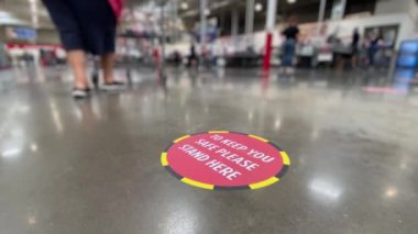 Büyük bir deponun zeminindeki sosyal uzaklık hatırlatma etiketinin düşük açılı görüntüsü.  