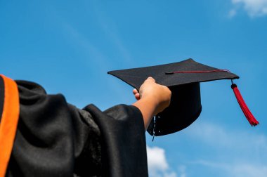 Mezuniyet şapkasını ellerinde tutan öğrenciler tören sırasında parlak bir gökyüzünde üniversiteden mezun oldular, Yüksekokulda Başarılı Eğitim Konsepti, 