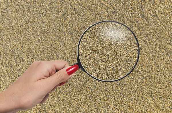 Magnifying glass enlarging grains of sand — Stock Photo, Image