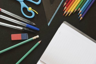 Okul ve ofis eşyaları bir defter ile karanlık bir yüzeye