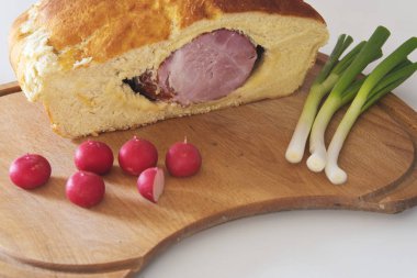 ham turp ve taze soğan ile birlikte bir kesme tahtası üzerinde bir ekmek