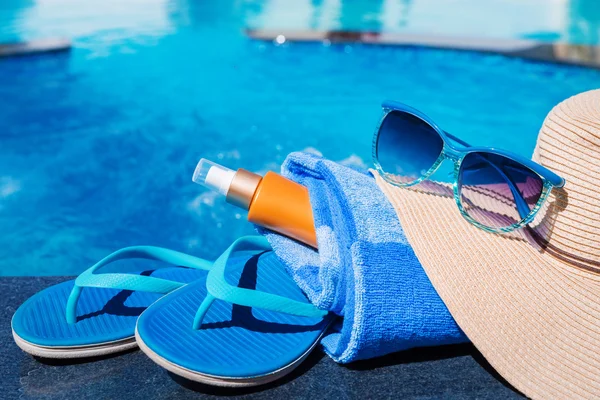 Chinelos azuis com protetor solar, toalha, chapéu de palha e protetor solar — Fotografia de Stock