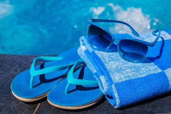 Zapatillas azules, gafas de sol y toalla en el borde de la piscina — Foto de Stock
