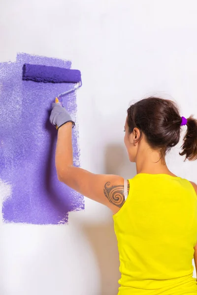 Kvinna målar väggen med lila vals — Stockfoto