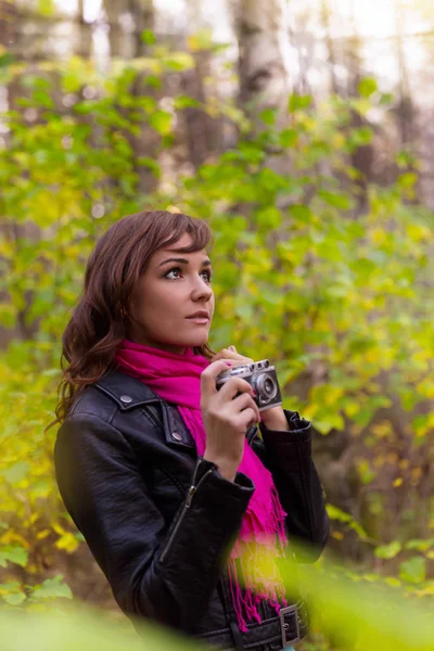 Donna bruna con una macchina fotografica nel parco autunnale — Foto Stock
