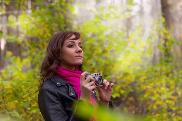 Donna bruna con una macchina fotografica nel parco autunnale — Foto Stock