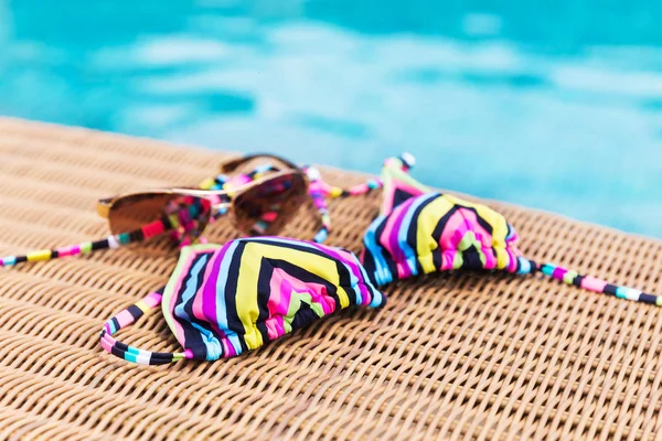 Gafas de sol y trajes de baño cerca de la piscina — Foto de Stock