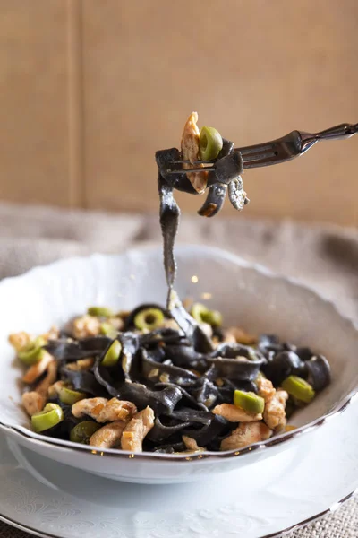 Schwarze Nudeln mit Huhn und grünen Oliven — Stockfoto