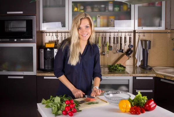 Bionda giovane donna cucina insalata in cucina — Foto Stock