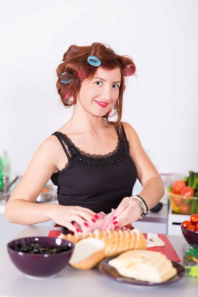 Žena v domácnosti, vaření s natáčky na vlasy — Stock fotografie