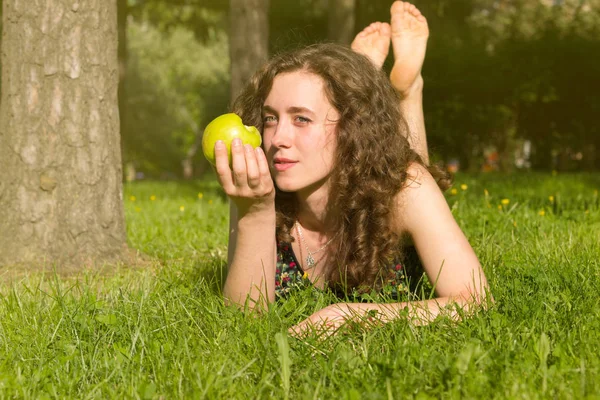 Jovem mulher bonita comendo maçã em um campo — Fotografia de Stock