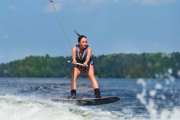 Slanke vrouw rijden wakeboard op Golf van boot — Stockfoto