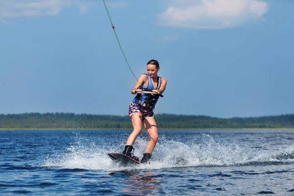 Slanke vrouw rijden wakeboard op Golf van boot — Stockfoto