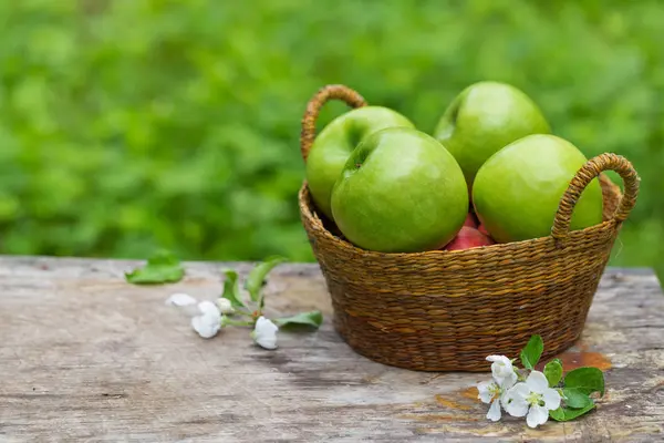 Söta saftiga röda gröna äpplen färska blommor på trä — Stockfoto
