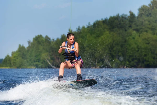 Slim brunette woman riding wakeboard on lake — Stock Photo, Image