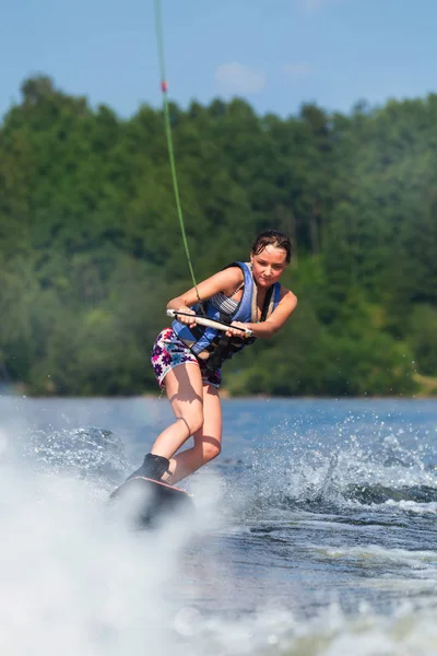 Slim brunette woman riding wakeboard on lake — Stock Photo, Image