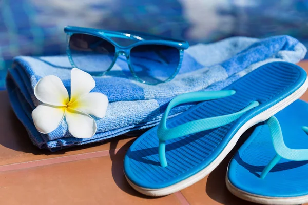 Blaue Hausschuhe, Sonnenbrille und Handtuch am Beckenrand — Stockfoto