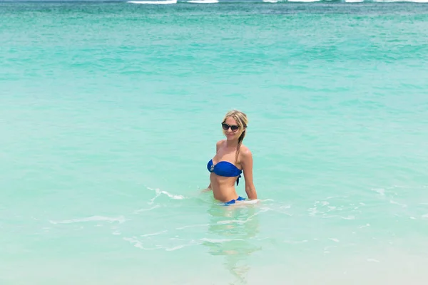 Junge hübsche blonde Frau im blauen Bikini am weißen tropischen Strand — Stockfoto