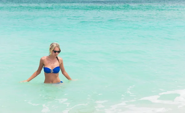 Joven mujer rubia bonita en bikini azul en la playa tropical blanca — Foto de Stock