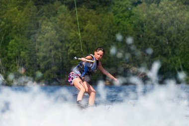 Genç oldukça ince esmer kadın mot dalga üzerinde wakeboard sürme