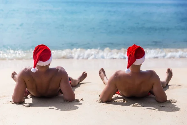 朝 hango のビーチでサンタ クロースの赤い帽子座っている二人の男 — ストック写真