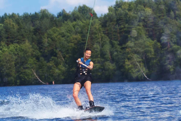 Young pretty slim brunette woman riding wakeboard on wave of mot — Stock Photo, Image