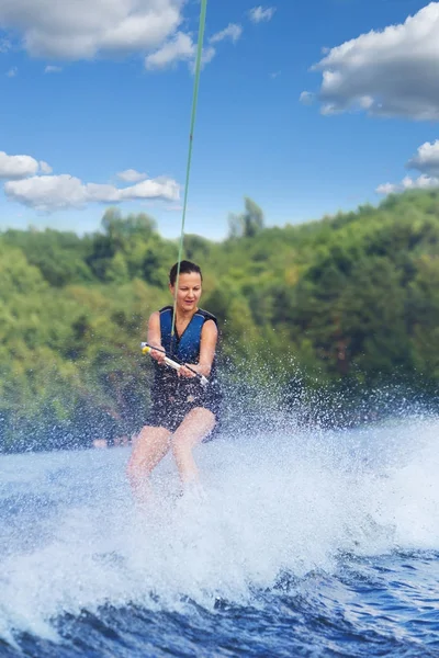 Young pretty slim brunette woman riding wakeboard on wave of mot — Stock Photo, Image