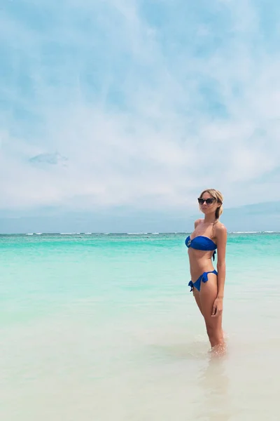 Junge hübsche blonde Frau im blauen Bikini am weißen tropischen Strand — Stockfoto