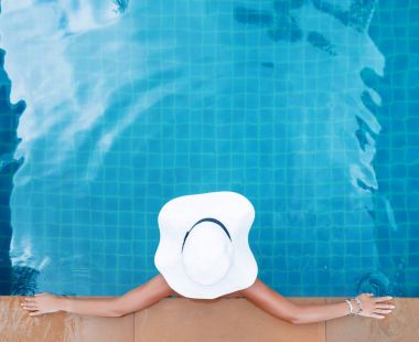 Hasır şapka yüzme havuzunda tropikal oturan genç ince kadın 