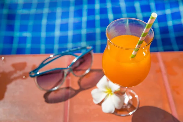Copo de bebida de suco de laranja fresco com flor e óculos de sol no bor — Fotografia de Stock